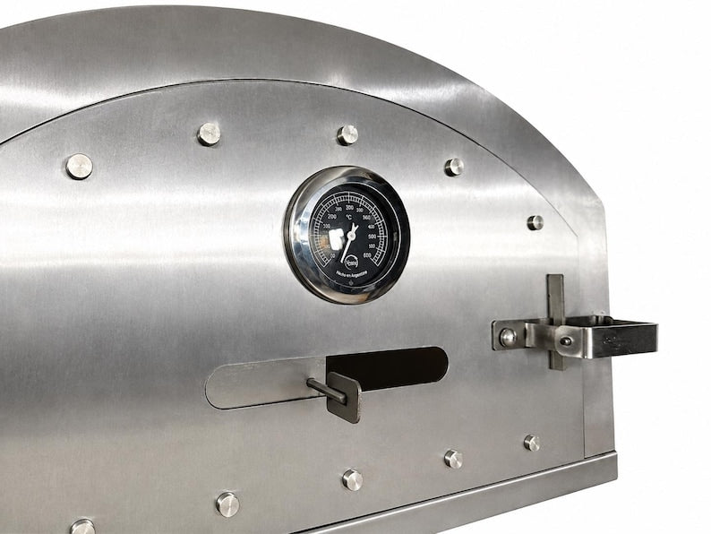 Stainless steel pizza oven door detail with thermometer and vent